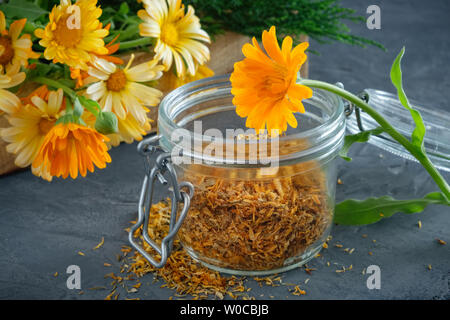 Fleurs de souci en bonne santé. Les herbes médicinales dans des caisses en bois et verre pot de pétales de calendula sèches. Banque D'Images