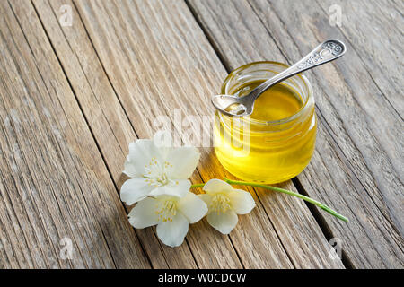 Petit pot de miel et Philadelphus ou jardin fleurs de jasmin sur planche de bois. Banque D'Images