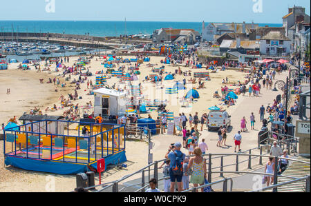 Lyme Regis, dans le Dorset, UK. 27 juin 2019. Météo France : Sunseekers se rendent dans la pittoresque station balnéaire de Lyme Regis pour profiter du soleil brûlant et lumineux ciel bleu comme la canicule saharienne hits au Royaume-Uni. Les visiteurs et les habitants se prélasser au soleil torride sur la plage de sable de la ville. Credit : Celia McMahon/Alamy Live News. Banque D'Images