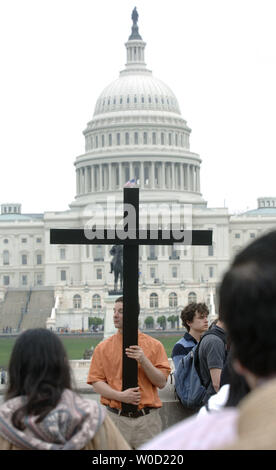 Mike Riconscente est titulaire d'une croix comme lui et d'autres chrétiens proie devant le Capitole au cours de la 'Vendredi Saint Chemin de Croix' martch sur le National Mall, parrainé par l'église Saint Pierre, à Washington le 14 avril 2006. (UPI Photo/Kevin Dietsch) Banque D'Images