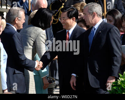 Le président chinois Hu Jintao (C) shanks mains avec le secrétaire de la Défense Donald Rumsfeld, alors que le président George W. Bush montre sur pelouse Sud, au cours d'une cérémonie d'arrivée à la Maison Blanche le 20 avril 2006. (UPI Photo/Kevin Dietsch) Banque D'Images