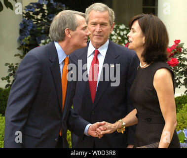 Le président américain George W. Bush (C) regarde comme nouvellement-assermenté Directeur de l'Office of Management and Budget Rob Portman (L) se penche pour embrasser sa femme, Jane, après la cérémonie dans la roseraie de la Maison Blanche, le 2 juin 2006. (Photo d'UPI/Mike Theiler) Banque D'Images