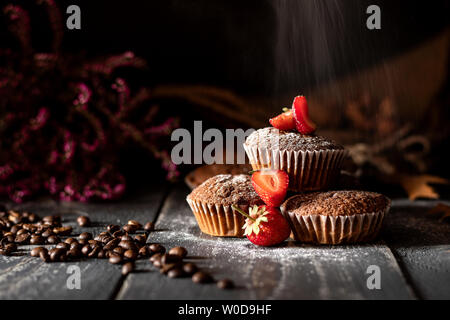 Le sucre sur muffins aux fraises posées sur un sac de jute avec des grains de café et Heather rose en arrière-plan. Banque D'Images