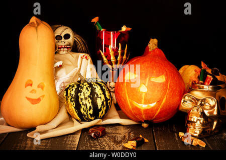 Halloween concept. Deux citrouilles sculptées avec une tasse de squelette et un crâne plein de bonbons. Banque D'Images