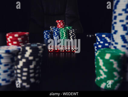 Close up des piles de jetons de couleurs différentes et jouer sur la table dés casino isolé sur fond noir. Tournoi de Jeu de pari Banque D'Images