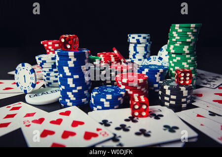 Close up pile de jetons de poker de différentes couleurs, jeux de cartes et dés plus isolés d'arrière-plan noir table de casino. Tournoi de Jeu gains, être Banque D'Images