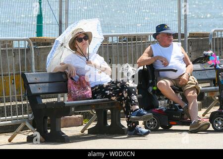 West Bay, Dorset, UK. 27 juin 2019. Météo britannique. Ombrage elle-même une femme avec un parapluie de la soleil brûlant à la station balnéaire de West Bay, dans le Dorset. Crédit photo : Graham Hunt/Alamy Live News Banque D'Images