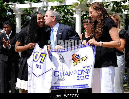 Le Président George Bush bisous Phoenix Mercury guard Cappie Pondexter tandis que sa coéquipière Diana Taurasi montres sur lors d'une cérémonie où Bush a honoré la WNBA 2007 champions, les Phoenix Mercury, dans l'Est du jardin de la Maison Blanche à Washington le 23 juin 2008. (UPI Photo/Kevin Dietsch) Banque D'Images