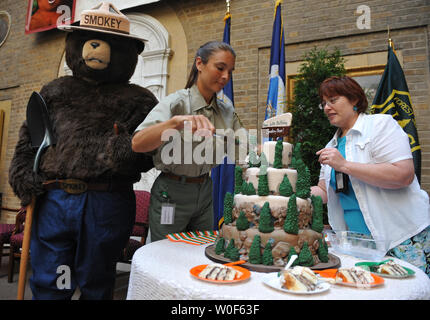 Personnel du service forestier a rejoint par un acteur habillé en l'ours Smokey couper le gâteau d'anniversaire au cours d'une cérémonie célébrant le 65e anniversaire de l'ours Smokey, au ministère de l'Agriculture des États-Unis à Washington le 10 août 2009. UPI/Kevin Dietsch Banque D'Images