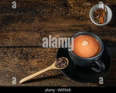 Tasse de chocolat aux épices (cannelle, girofle et ANIS) et mortier sur une authentique ancienne table Banque D'Images