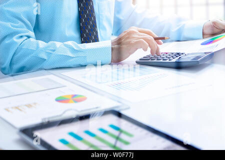 Businessman touching calcolator profondément enfoncés tout en examinant un rapport financier pour un retour sur investissement ou d'analyse des risques d'investissement et performa Banque D'Images