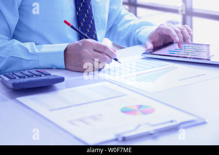 Businessman touching tablet écran lors de l'examen d'un profondément rapports financiers pour un retour sur investissement ou d'investissement l'analyse des risques et des performances. Banque D'Images