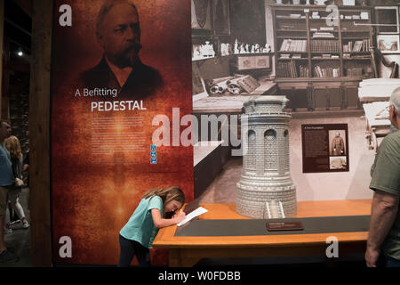 Une fille visiter la statue de la liberté Musée sur Liberty Island a pris des notes sur le piédestal de la statue, qui a été conçu par Richard Morris Hunt. Banque D'Images