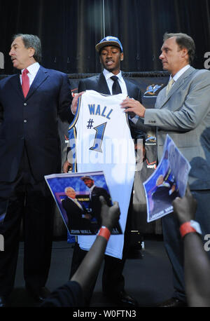John Wall (C), la NBA # 1 de draft par les Washington Wizards, est titulaire d'un des assistants les assistants aux côtés de jersey Président Ernie Grunfeld (L) et entraîneur Flip Saunders lors d'une conférence de presse au Verizon Center à Washington le 25 juin 2010. Photos d'enfants tenant au mur la draft pour demander son autographe. UPI/Alexis C. Glenn Banque D'Images