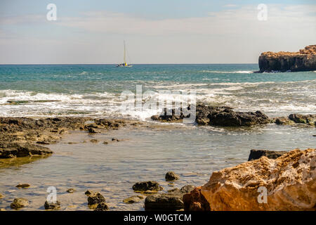 Clapotis des vagues sur le rivage de la Méditerranée près de Torrevieja en Espagne en tant que bateau à voile va par Banque D'Images