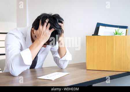 Stressed businessman va être démission et effets personnels d'emballage société et fichiers dans boîte en carton brun, changeant et démissionnera de travail conceptuel Banque D'Images