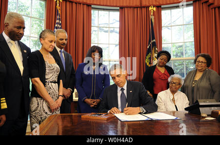 Le président américain Barack Obama signe une loi dans le bureau ovale, le 24 mai 2013 à Washington, DC, désignant la médaille d'or du Congrès commémorant la vie des quatre jeunes filles tuées dans l'Église baptiste à l'explosif de 1963 à Birmingham, Alabama. Témoins (L-R) Birmingham maire William Bell, Dr Sharon Malone titulaire, le procureur général Eric Holder, Rep Terri Sewell (D-AL), Thelma Pippen McNair (mère de Denise McNair), Lisa McNair (soeur de Denise McNair), Dianne Braddock (soeur de Carole Robertson). UPI/Mike Theiler. . Banque D'Images