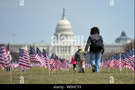 Une femme et un enfant à pied entre certaines des 1 892 drapeaux américains mis sur le National Mall par l'Iraq et l'Afghanistan Veterans of America, chaque drapeau représente l'un des 1 892 anciens combattants et membres de service qui se sont suicidés cette année, à Washington, D.C., le 27 mars 2014. Le monument fait partie de la 'Nous avons votre retour : l'IAVA Campagne pour lutter contre le suicide UPI/Kevin Dietsch Banque D'Images