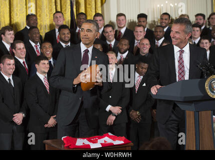 Le président Barack Obama est titulaire d'un football aux côtés de l'entraîneur-chef de l'état de l'Ohio Buckeye Urban Meyer comme Obama honore les éliminatoires de football 2015 Champions nationaux Université de l'Ohio State Buckeyes dans l'East Room à la Maison Blanche, à Washington, D.C. le 20 avril 2015. Photo par Kevin Dietsch/UPI Banque D'Images