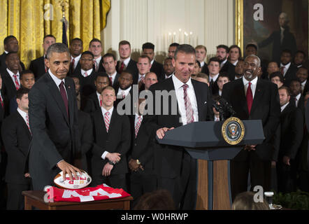 Le président Barack Obama est titulaire d'un football aux côtés de l'entraîneur-chef de l'état de l'Ohio Buckeye Urban Meyer comme Obama honore les éliminatoires de football 2015 Champions nationaux Université de l'Ohio State Buckeyes dans l'East Room à la Maison Blanche, à Washington, D.C. le 20 avril 2015. Photo par Kevin Dietsch/UPI Banque D'Images