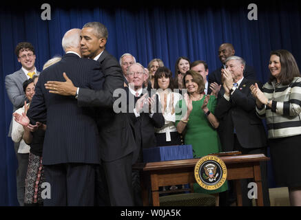 Le président Barack Obama hugs le Vice-président Joe Biden après la signature de la Loi sur les traitements du 21e siècle en tant que législateurs et partisans applaudir, lors d'une cérémonie à l'Eisenhower Executive Office Building à Washington, D.C. le 13 décembre 2016. Ce projet de loi va faire de nouveaux investissements pour répondre à l'épidémie d'héroïne et d'opiacés d'ordonnance, d'accélérer les découvertes en recherche contre le cancer, dans le cadre de la Cancer Moonshot, développez l'Administration son cerveau et d'initiatives de médecine de précision, et de prendre des mesures importantes pour améliorer la santé mentale et la Food and Drug Administration's processus de développement des médicaments. Photo par Kevi Banque D'Images