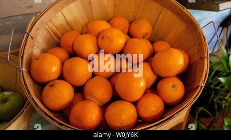 Panier en rotin rempli d'agrumes frais sur un buffet ou table du marché aux côtés de la pomme verte dans un close up high angle view Banque D'Images