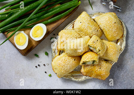 La cuisine russe traditionnelle. Oeufs tartes et les oignons verts sur la lumière table en pierre. Vue supérieure de la télévision. Banque D'Images
