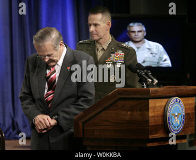 Secrétaire américain à la défense, Donald Rumsfeld, à gauche, et le Général Peter Pace, président de l'état-major interarmées, d'écouter une traduction live TV d'Iraq du commandant, Multi-National Force-Iraq Général George Casey lors d'une réunion publique du Pentagone à Washington, le 15 décembre 2005. (Photo d'UPI/Yuri Gripas) Banque D'Images