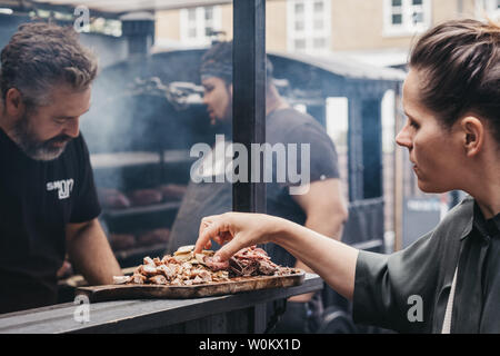 Londres, Royaume-Uni - Juin 22,2019 : viande grillée d'échantillonnage à un Smokoloco Marché de Spitalfields, décrochage à l'intérieur de l'une des plus belles salles de marché victorien dans Lo Banque D'Images