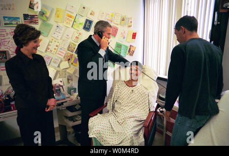 Le Président George Bush parle d'un parent de sergent de l'armée américaine Première Classe Joseph Briscoe, de liberté, Texas, après avoir présenté de lui le Purple Heart pour blessures Sgt. Briscoe subie alors qu'il en poste en Iraq. Les troupes de la visite du président Bush au Walter Reed Army Medical Center à Washington, D.C., le jeudi 18 décembre 2003. Laura Bush et le Sgt. Le frère de Briscoe, Ira, regarde. (UPI Photo/Eric Draper/maison blanche) Banque D'Images