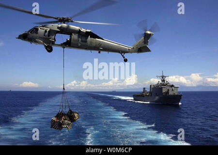 Un U.S. Navy hélicoptère MH-60S Knighthawk palettes de fret transporte au dock landing ship USS Fort McHenry (LSD 43) lors d'un ravitaillement vertical le 14 janvier 2005. Les hélicoptères et les marins affectés à l'USS ABRAHAM LINCOLN (CVN 72) Carrier Strike Group appuient l'opération Unified Assistance, l'opération humanitaire d'efforts à la suite du tsunami qui a frappé l'Asie du Sud Est. (Photo/UPI/NAVY) Jeremie Yoder Banque D'Images