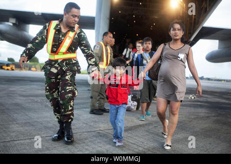 Airman avec la Philippine Air Force contribue à décharger les civils philippins d'un Marine américain C-130 Hercules au Villamor Air Base, aux Philippines, le 12 novembre 2013 que les Marines des États-Unis d'aider dans les efforts de secours à la suite du typhon Hiyan. Le personnel militaire américain sont d'aider les Forces armées philippines en fournissant une aide humanitaire et des secours aux zones touchées partout aux Philippines à la suite du typhon meurtrier qui a fait 2 357 morts. Codey Underwood/UPI/USMC Banque D'Images