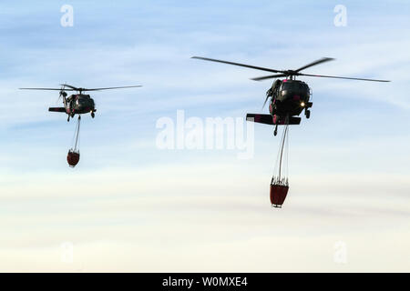 Une paire de Californie National Guard hélicoptères UH-60 Black Hawk de la Compagnie B, 1er Bataillon, 140e Régiment d'aviation, de la terre pour faire le plein à l'aéroport de Camarillo de Camarillo, Californie, le 9 décembre 2017. Les hélicoptères ont passé la journée à l'abandon de l'eau sur le feu Thomas, en coordination avec le feu. Par Thomas samedi soir, le feu a brûlé 173 000 hectares et détruit plus de 500 depuis le début de ses structures le 4 décembre. Photo par SrA Housman Crystal/U.S. Air National Guard/UPI Banque D'Images