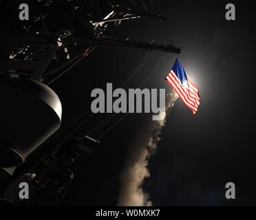 Un missile de croisière illumine le drapeau américain que le destroyer USS-missiles Porter (DDG 78) effectue des opérations de grève alors que dans la mer Méditerranée, le 7 avril 2017. Porter, l'avant-déployé à Rota, Espagne, mène des opérations navales dans la sixième flotte américaine zone d'opérations à l'appui de la sécurité nationale des États-Unis en Europe. Le président Donald Trump le jeudi soir a dit qu'il a ordonné 59 missiles de croisière pour attaquer l'aérodrome où le président syrien Bachar al-Assad's régime a lancé une attaque chimique mortel sur les civils deux jours plus tôt. U.S. Navy photo de classe 3ème MCS Ford vous Banque D'Images