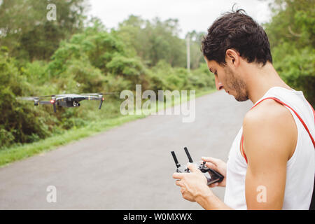 Jeune homme en vol avec le drone dans une route Banque D'Images