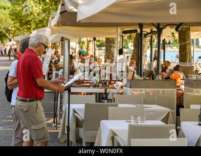 GARDA, ITALIE - Septembre 2018 : deux personnes étudiant le menu d'un restaurant au bord du lac de Garda, sur le lac de Garde. Banque D'Images