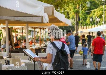 GARDA, ITALIE - Septembre 2018 : deux personnes étudiant le menu d'un restaurant au bord du lac de Garda, sur le lac de Garde. Banque D'Images