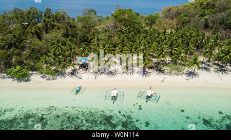 Bateaux traditionnels philippins situé dans une plage tropicale avec palmiers et sable blanc dans une journée ensoleillée. Destination de voyage aux Philippines Banque D'Images