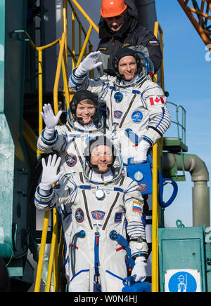 L'ingénieur de vol de l'expédition 58 David Saint-Jacques de l'Agence spatiale canadienne (ASC), haut, mécanicien de Anne McClain, centre de la NASA, et commandant de Soyouz Oleg Kononenko de Roscosmos, bas, adieu l'onde avant d'embarquer sur le vaisseau Soyouz MS-11 pour lancer, le 3 décembre 2018, à Baïkonour, au Kazakhstan. Kononenko. McClain, Saint-Jacques et passera les six mois et demi à bord de la Station spatiale internationale. Photo de la NASA par Aubrey Gemignani/UPI Banque D'Images