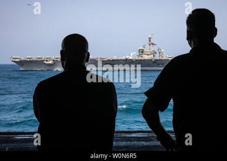 Mécanicien en chef Blake Morton, gauche, et chef de l'Hospital Corpsman John Buxton regarder la classe Nimitz porte-avions USS ABRAHAM LINCOLN (CVN 72) aux côtés de la vapeur à partir de la zone de la classe Wasp-navire d'assaut amphibie USS Kearsarge (DG 3) le 17 mai 2019. L'Abraham Lincoln (ABECSG) et groupe amphibie Kearsarge (KSGARG) mènent des opérations conjointes dans la 5e flotte américaine zone d'opérations. Le ABECSG KSGARG et, avec l'entrepris 22e Marine Expeditionary Unit, sont prêts à faire face aux imprévus et de défendre les intérêts et les forces américaines dans la région Banque D'Images