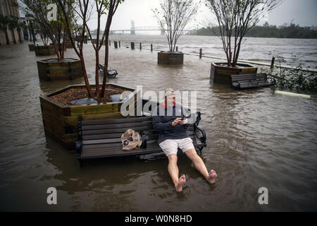 Ray Baca, de Wilmington, Caroline du Nord, vérifie son téléphone comme il est assis sur un banc, comme le flux de la rivière Cape Fear sur South Water St., après l'ouragan Florence a frappé, le 14 septembre 2018 à Wilmington, Caroline du Nord. Photo par Al Drago/UPI Banque D'Images