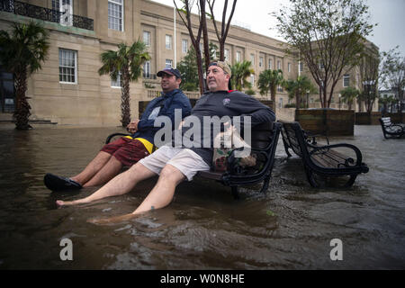 Mark Anthony Mueller, gauche, et Ray Baca, tous deux de la Wilmington, s'asseoir sur un banc, comme le flux de la rivière Cape Fear sur South Water St., après l'ouragan Florence a frappé, le 14 septembre 2018 à Wilmington, Caroline du Nord. Photo par Al Drago/UPI Banque D'Images