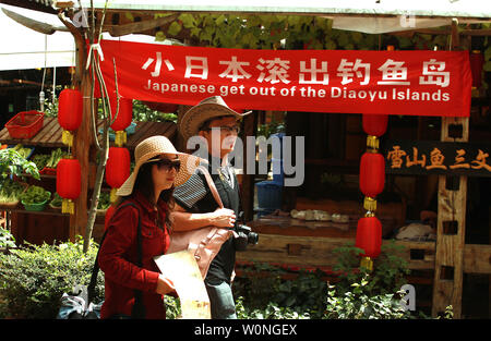 Un couple chinois passe devant un restaurant de l'affichage d'une bannière anti-japonais sur son entrée à Lijiang, dans le nord de la province du Yunnan, le 27 septembre 2012. UPI/Stephen Shaver Banque D'Images