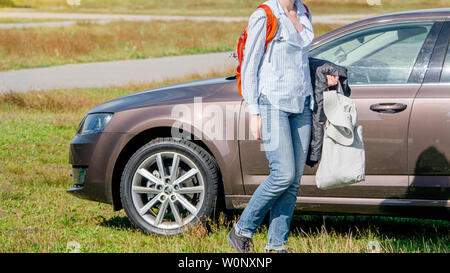 IJmuiden Santpoort Zuid, Pays-Bas - Aug 20, 2018 : femme d'arriver à la réalisation des vêtements et accessoires de plage près de new Skoda Octavia garée sur le vaste stationnement de plage Banque D'Images