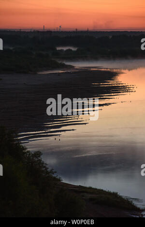 Nuit sur les rives de la rivière avec l'augmentation du brouillard et beaucoup d'oiseaux assis au bord de l'eau sur la rive. Banque D'Images