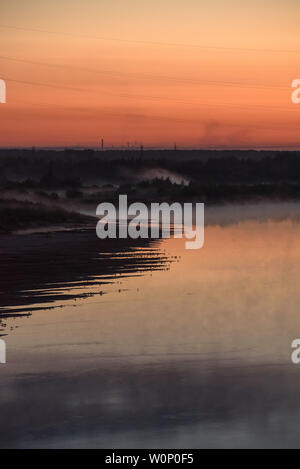 Nuit sur les rives de la rivière avec l'augmentation du brouillard et beaucoup d'oiseaux assis au bord de l'eau sur la rive. Banque D'Images