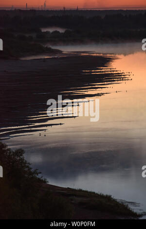 Nuit sur les rives de la rivière avec l'augmentation du brouillard et beaucoup d'oiseaux assis au bord de l'eau sur la rive. Banque D'Images