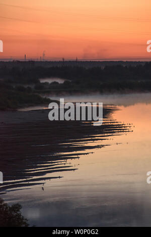 Nuit sur les rives de la rivière avec l'augmentation du brouillard et beaucoup d'oiseaux assis au bord de l'eau sur la rive. Banque D'Images