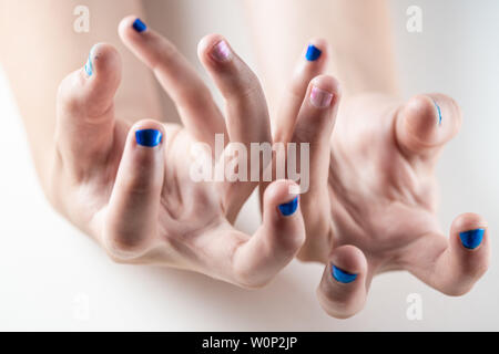 Une mère peint ses mains de jeune fille en bleu et rose nailpolish, considéré dans un cas isolé sur fond blanc Banque D'Images