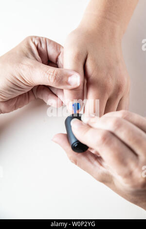 Une mère peint ses mains de jeune fille en bleu et rose nailpolish, considéré dans un cas isolé sur fond blanc Banque D'Images